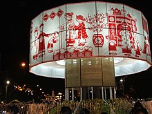 A large round white fabric band decorated with red figures and images for Tết