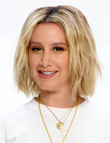 A woman with long blonde hair wearing a white t-shirt.