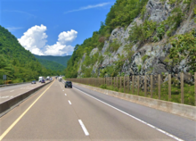 A stretch of highway, with a fence along the side to keep rocks out of the road