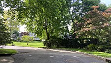 The former site of the Flower Hill School. After the school closed, the land was sold, sub-divided, and now contains multiple single-family homes. Note part of the former school's fence and the old, faded school district sign attached to it.