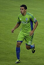 A man wearing a green shirt and shorts. He is running