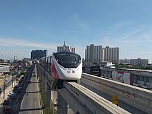 A pink line monorail train about to pull into a station