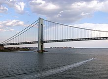 View of the Verrazzano-Narrows Bridge looking south from Upper New York Bay. The neighborhood of Coney Island in Brooklyn can be seen in the distance.