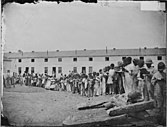 A contraband school, held outdoors. Note teacher, in coat and tie, on mound at left.