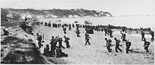 American troops on a beach near Algiers, behind a large U.S. flag