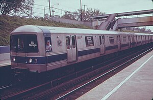 Train at a station, with its driver leaning out the window to pose for the camera