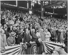 A wide shot with United States president Harry Truman in the center throwing a baseball.