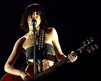 A girl singing and playing a guitar on stage