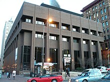 A gray brutalist building on a street corner in an urban environment