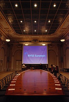 The boardroom, which contains seats on either side of a curving wooden table, facing a projection screen