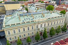 Aerial view of an old, square building with trees in front