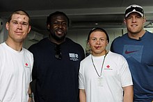 The two football players standing aside two recovering soldiers