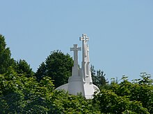 Three white stone crosses, surrounded by vegetation