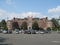 A seven-story brick hospital building with a parking lot