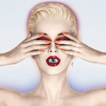 Katy Perry with blonde short hair. She covers her eyes with her hands; an eyeball is visible inside her mouth as her lips are slightly parted.