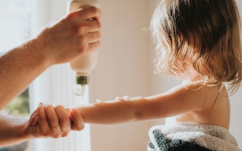 A parent applies an aftersun cream to their child