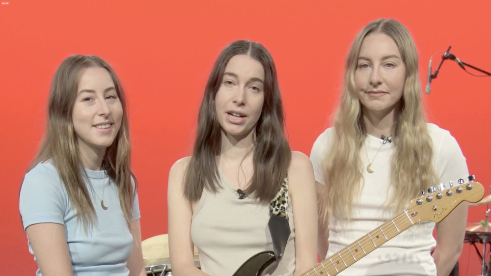 HAIM in front of an orange background