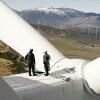 Technicians inspecting wind turbine blades overlooking landscape