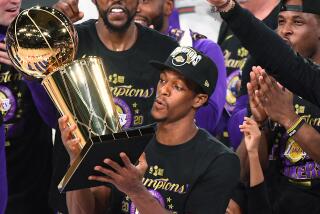 Rajon Rondo is surrounded by his teammates as he holds the trophy after the Lakers won the 2020 NBA championship.