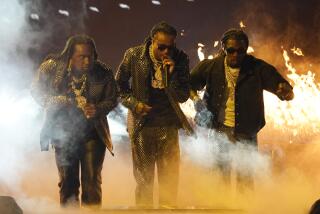 Three men in black outfits performing on a foggy stage