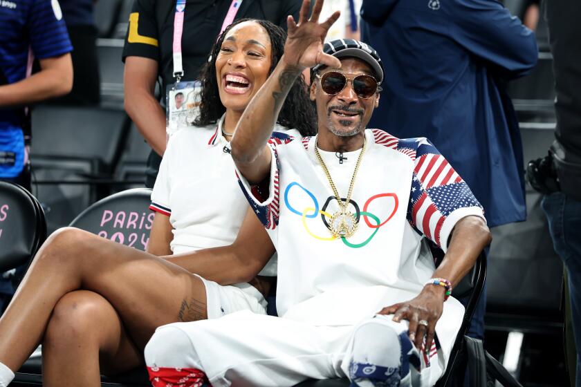 PARIS, FRANCE August 6, 2024-USA women's basketball player A'ja Wilson laughs with rapper Snoop Dogg before a mens game against Brazil at the 2024 Paris Olympics Tuesday. (Skalij/Los Angeles Times)