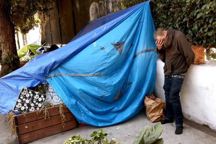 VENICE, CA - JULY 10, 2024 - A homeless man stands in front of this tent along 200 Grand Canal Street a block from where the Venice Dell Project is to be built as housing for the homeless in Venice on July 10, 2024. Advocates for low-income housing are suing the city of Los Angeles this week accusing City Council member Traci Park, City Atty. Hydee Feldstein Soto and other officials of violating fair housing laws by allegedly blocking a planned affordable housing development in Venice. The Venice Dell project is to include 140 units of housing for low-income and formerly homeless residents on what's now a city-owned parking lot along the neighborhood's famed canals. (Genaro Molina/Los Angeles Times)