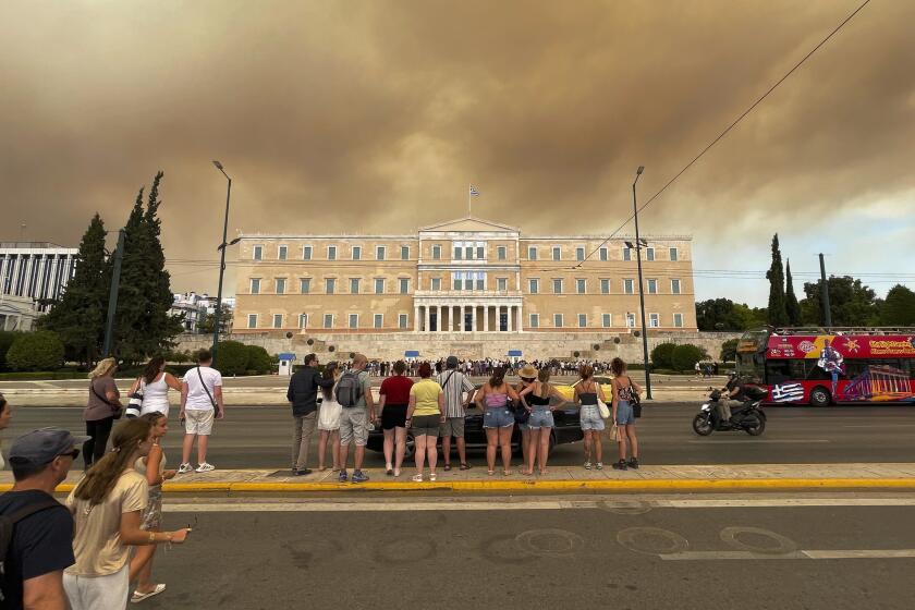 Smoke from wildfires is seen above the Greek parliament building in central Athens, Sunday, Aug. 11, 2024, after a blaze northeast of the capital forced evacuations in the area. (AP Photo/Derek Gatopoulos)