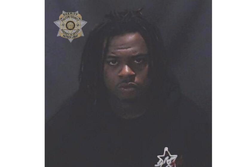 A police mug shot of a man with dark braided hair