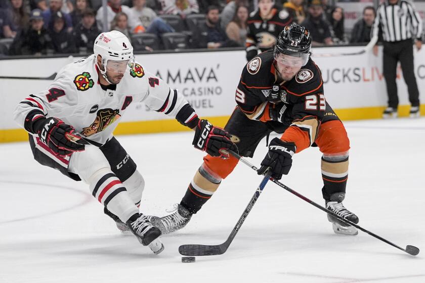 Anaheim Ducks center Mason McTavish, right, shoots against Chicago Blackhawks defenseman Seth Jones.