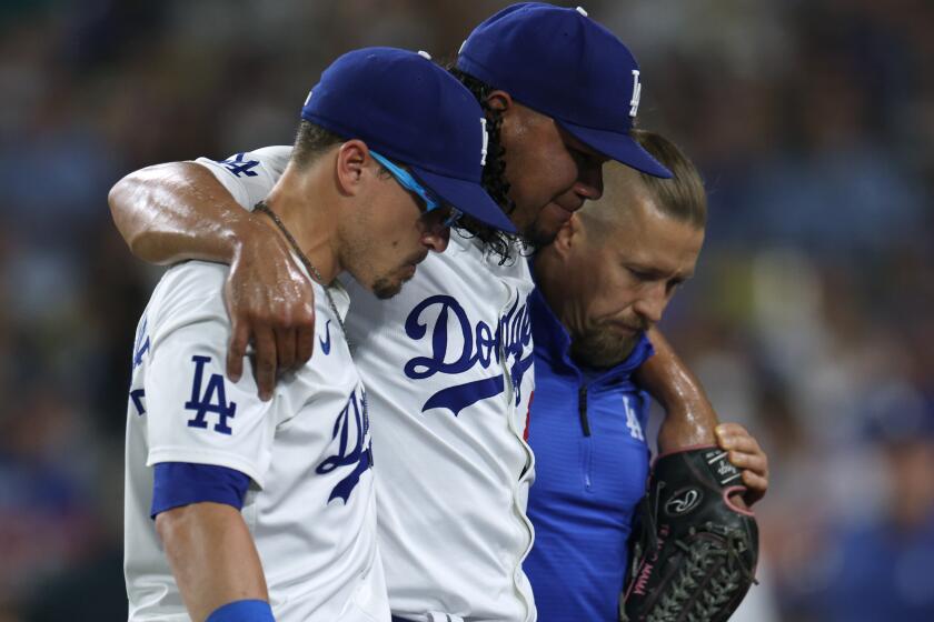 Brusdar Graterol is helped off the field by Kiké Hernández and medical staff during the sixth inning.