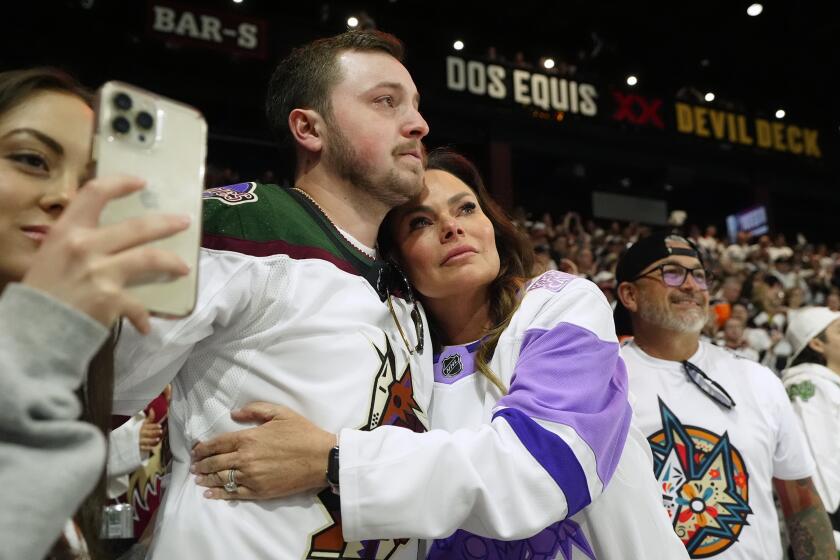 Arizona Coyotes season-ticket holders comfort one another as time expires during the team's game Wednesday 