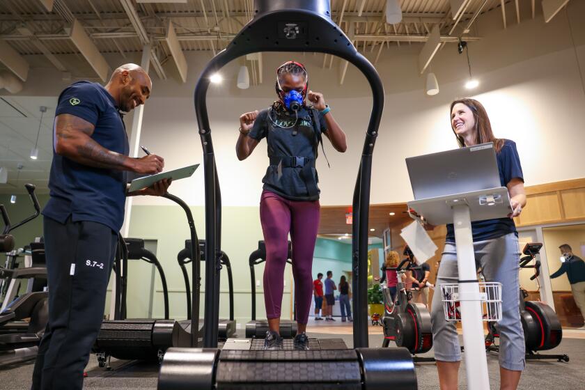 EL SEGUNDO-CA-AUGUST 2, 2024: Exercise physiologist Davon Murray, left, and physical therapist Danel Lombard, right, demonstrate the VO2 Max on personal trainer Shelle Tarver, center, at Love.Life, a holistic health and wellness club, in El Segundo on August 2, 2024. (Christina House / Los Angeles Times)