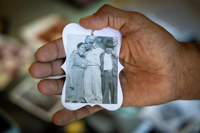 San Juan Capistrano, CA - July 03: Larry Herrera-Cabrera, shown holding a photo of his maternal uncle Joe with Joe's parents, whose family (and that of his wife) were removed from Chavez Ravine in the 1950s to make way for Dodger Stadium, talks about his point of view at his home in San Juan Capistrano Wednesday, July 3, 2024. Larry is skeptical about a proposed Assembly bill that would give reparations to Chavez Ravine families. (Allen J. Schaben / Los Angeles Times)