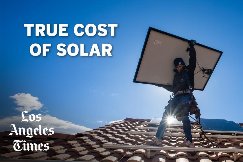 A worker lifts a solar panel above his head on top of a roof during installation. 