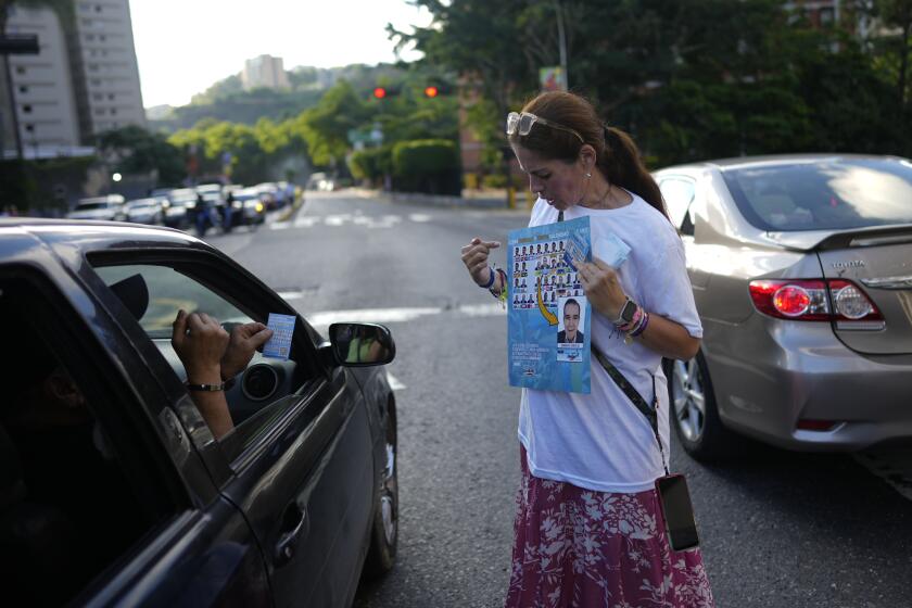 A supporter of opposition presidential candidate Edmundo Gonzalez shows how to vote for him during pass out campaign flyers in Caracas, Venezuela, Friday, July 19, 2024. The presidential election is set for July 28. (AP Photo/Ariana Cubillos)