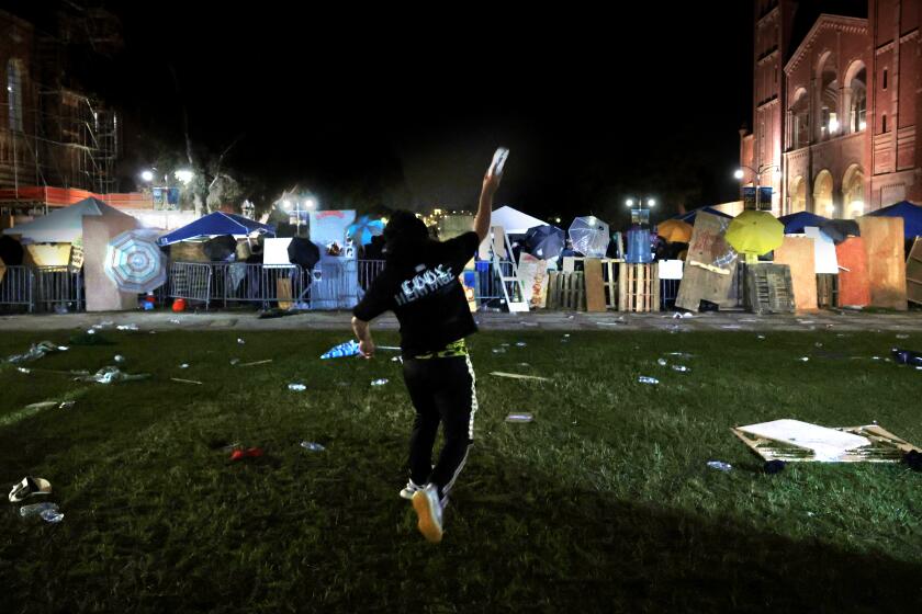 LOS ANGELES, CALIFORNIA - May 1: A pro-Israeli supporter throws a bottle of water at the Pro-Palestinian encampment at UCLA early Wednesday morning. (Wally Skalij/Los Angeles Times)