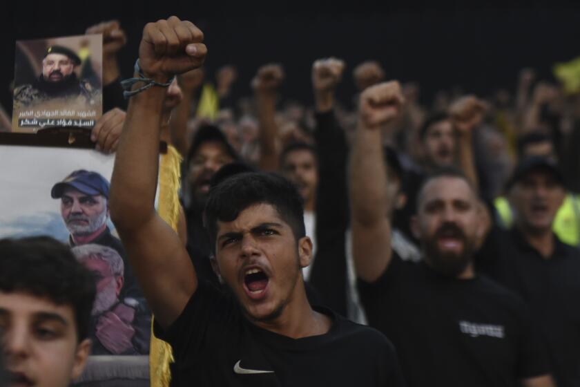 Supporters raise their fists and cheer as they watch a speech given by Hezbollah leader Sayyed Hassan Nasrallah on a screen during a ceremony to commemorate the death of top commander Fouad Shukur, who was killed by an Israeli airstrike last week, in Beirut, Lebanon, Tuesday, Aug. 6, 2024. (AP Photo/Mustafa Jamalddine)