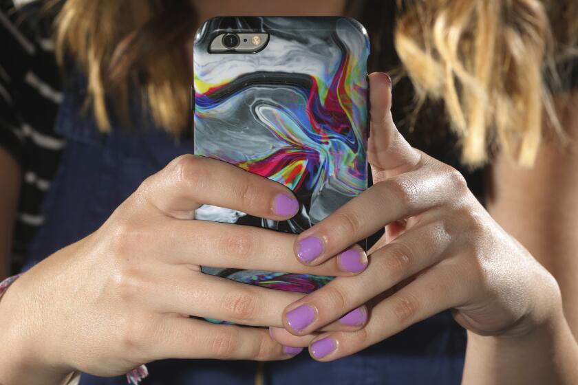 In this Monday, July 22, 2019, photo, Rachel Whalen looks at her phone at her home in Draper, Utah. Whalen remembers feeling gutted in high school when a former friend would mock her online postings, threaten to unfollow or unfriend her on social media and post inside jokes about her to others online. The cyberbullying was so distressing that Whalen even contemplated suicide. There's a rise in cyberbullying nationwide, with three times as many girls reporting being harassed online or by text message than boys, according to the National Center for Education Statistics. (AP Photo/Rick Bowmer)