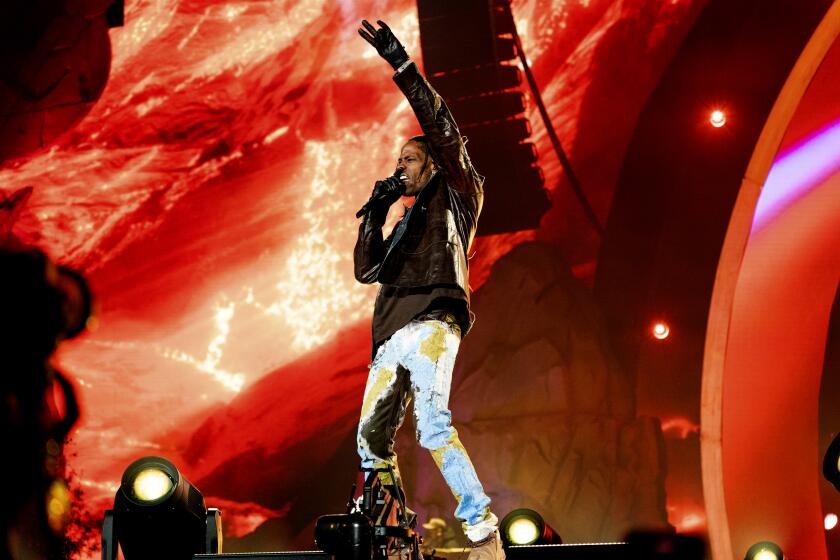 A man raising his arm and vocalizing into a microphone on a stage