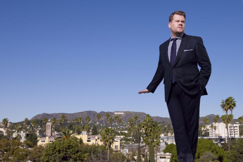 A man in a blue suit poses with mountains and blue skies in the background