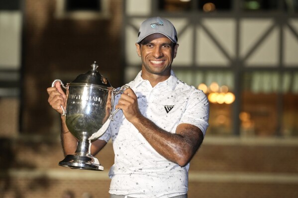 Aaron Rai, of England, poses with the trophy after winning the Wyndham Championship golf tournament in Greensboro, N.C., Sunday, Aug. 11, 2024. (AP Photo/Chuck Burton)