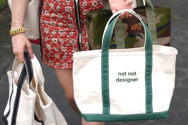 Gracie Wiener poses for a photo with some of her tote bags in Washington Square Park in New York, Wednesday, July 17, 2024, (AP Photo/Pamela Smith)