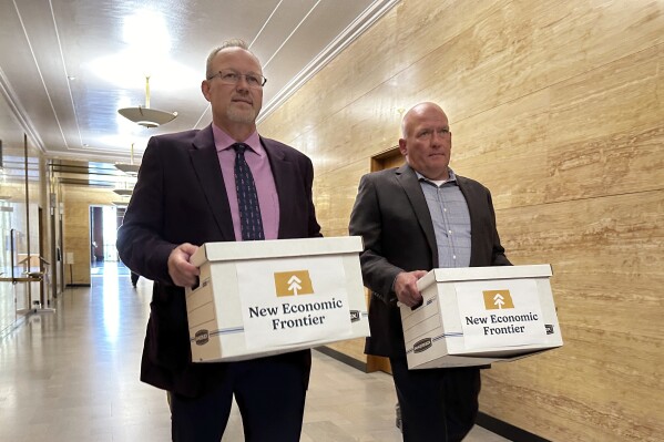 FILE - Steve Bakken, left, and Casey Neumann, of the New Economic Frontier ballot initiative group, carry boxes containing petitions to the Secretary of State's Office on Monday, July 8, 2024, at the state Capitol in Bismarck, N.D. (AP Photo/Jack Dura, File)