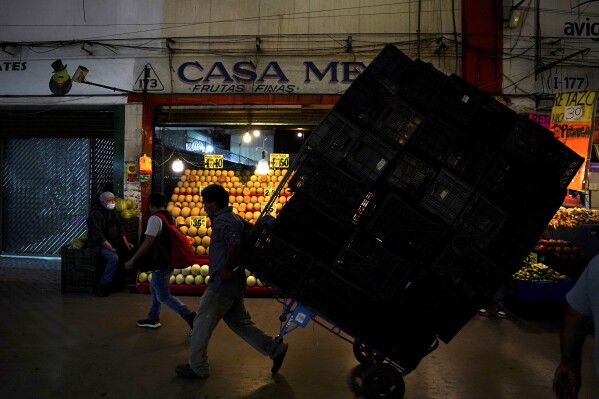 FILE - A porter hauls a load of crates at the Central de Abastos, the largest wholesale food and goods market, in Mexico City, Aug. 3, 2022. (AP Photo/Fernando Llano, File)