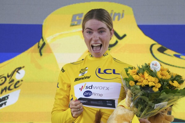 Stage winner Demi Vollering of The Netherlands, wearing the overall leader's yellow jersey, celebrates on the podium after the third stage of the Tour de France Women cycling race, an individual time trial with start and finish in Rotterdam, Netherlands, Tuesday, Aug. 13, 2024. (AP Photo/Peter Dejong)