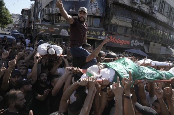 Mourners carry the bodies of five Palestinians during their funeral, draped in flags of the Hamas and Islamic Jihad militant groups, killed by an Israeli strike on a vehicle in the West Bank city of Jenin, Tuesday, Aug. 6, 2024. (AP Photo/Majdi Mohammed)