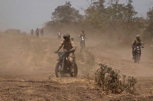 In this photo taken from video released by Russian Defense Ministry Press Service on Monday, Aug. 12, 2024, marine assault team members ride motorcycles toward Ukrainian position at an undisclosed location. (Russian Defense Ministry Press Service photo via AP)