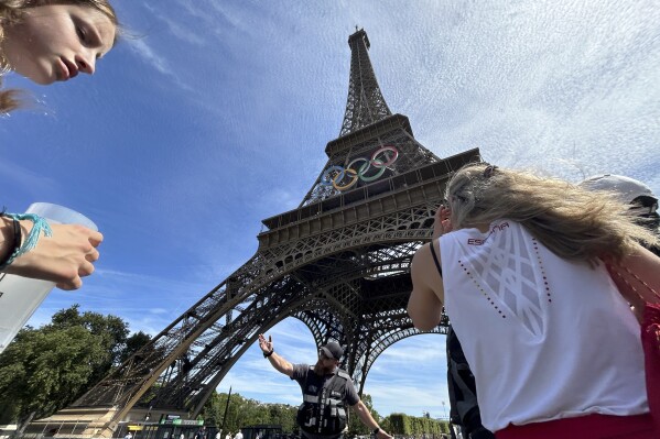 Police evacuate the area around the Eiffel Tower after a man was seen climbing the historic landmark, during the 2024 Summer Olympics, Sunday, Aug. 11, 2024, in Paris France. (AP Photo/Aijaz Rahi)