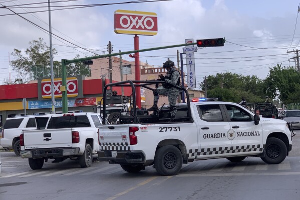 Mexican soldiers stand guard outside an Oxxo grocery shop near the Tamaulipas Chamber of Commerce, where its president Julio Cesar Almanza was killed, in Matamoros, Mexico, Tuesday, July 30, 2024. (AP Photo/Veronica Cisneros)