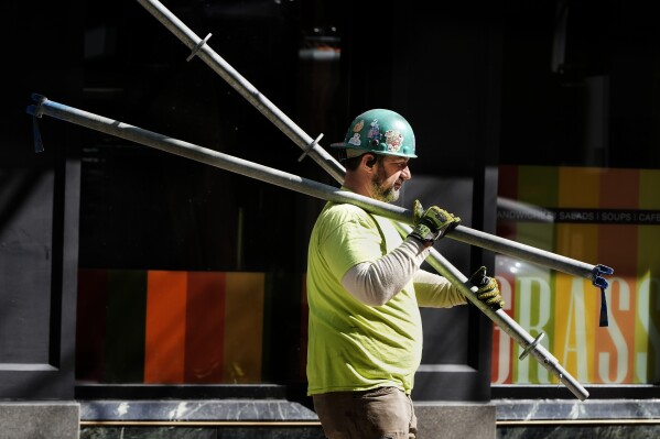 FILE - A construction worker carries scaffolding parts on March 14, 2024, in Boston. On Friday, August 2, 2024, the U.S. government issues its July jobs report. (AP Photo/Michael Dwyer, File)